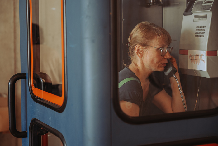 Eine Frau sitz in einer umgestalteten alten Telefonzelle und hört etwas an.